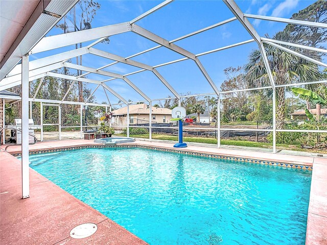 view of swimming pool with glass enclosure, a patio area, and an in ground hot tub