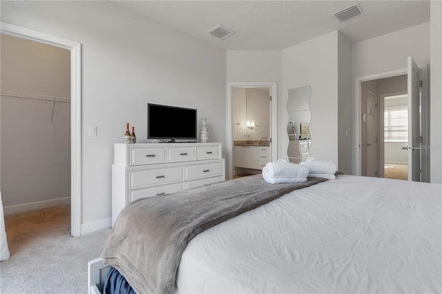 bedroom with a walk in closet, ensuite bathroom, a closet, and light colored carpet