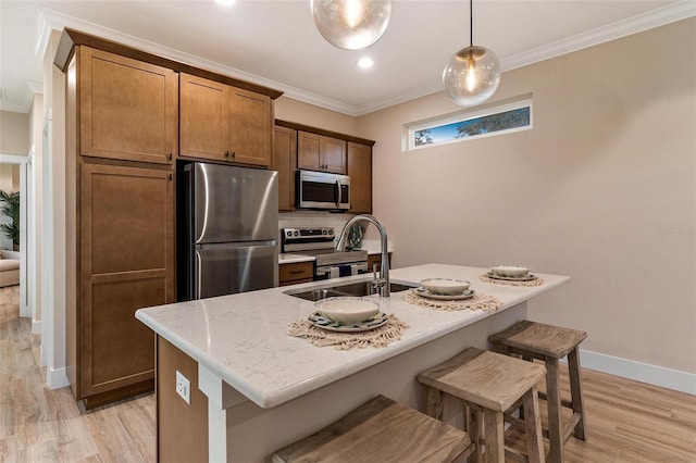 12133 Grand Oak Ln, Oxford, FL 34484 - kitchen featuring a center island with sink, hanging light fixtures, sink, light hardwood / wood-style flooring, and appliances with stainless steel finishes