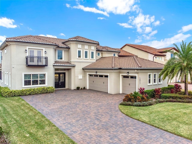 mediterranean / spanish-style house with an attached garage, a balcony, french doors, decorative driveway, and stucco siding