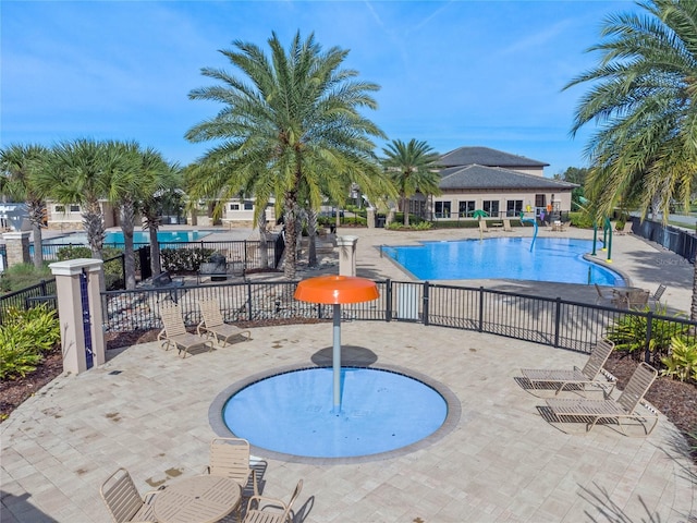 community pool with a patio area and fence