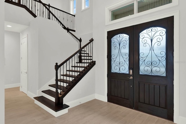 entrance foyer featuring a towering ceiling, wood finished floors, and french doors