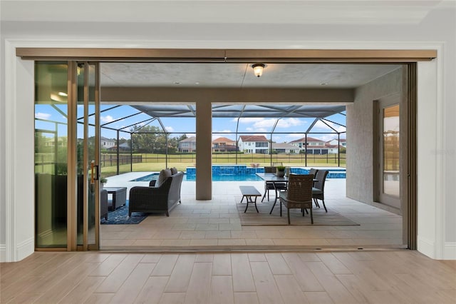 doorway featuring a sunroom, plenty of natural light, and wood finished floors