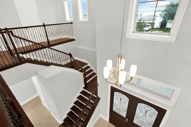 entrance foyer featuring a healthy amount of sunlight, light wood-type flooring, stairway, and a notable chandelier