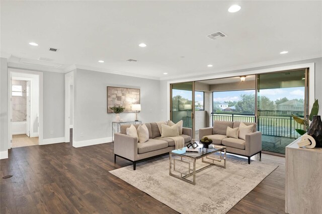 living area with ornamental molding, dark wood finished floors, and visible vents