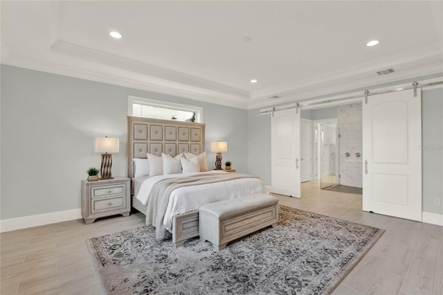 bedroom featuring a barn door, a tray ceiling, and ornamental molding