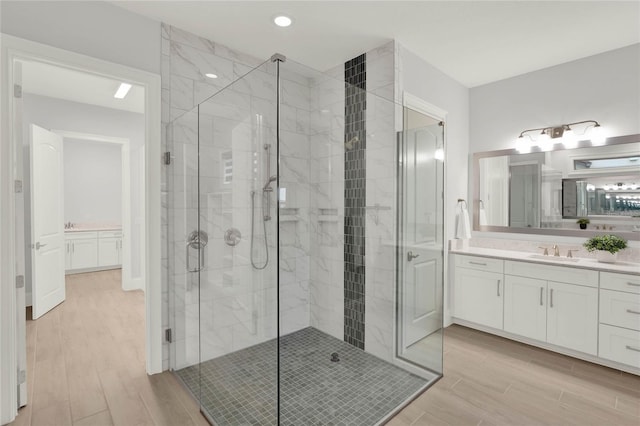 bathroom featuring wood finish floors, vanity, and a stall shower