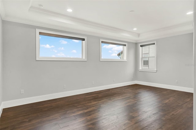 empty room featuring dark wood-style floors, a tray ceiling, and ornamental molding