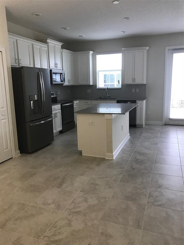 kitchen with plenty of natural light, a kitchen island, white cabinetry, and appliances with stainless steel finishes