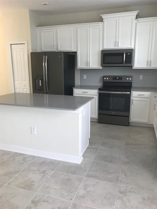 kitchen with backsplash, stainless steel appliances, white cabinetry, and light tile patterned flooring