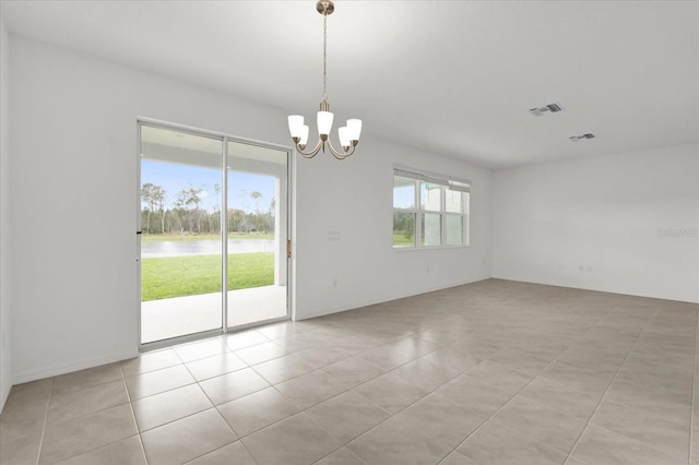 empty room with a water view, visible vents, a notable chandelier, and light tile patterned flooring