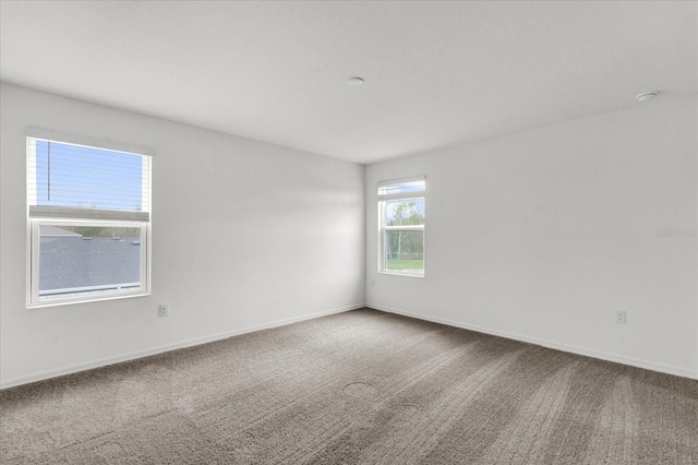 carpeted spare room featuring baseboards