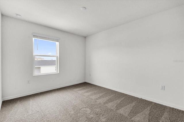 carpeted spare room featuring baseboards