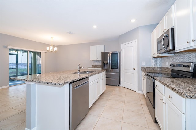 kitchen with backsplash, stainless steel appliances, white cabinetry, and a center island with sink