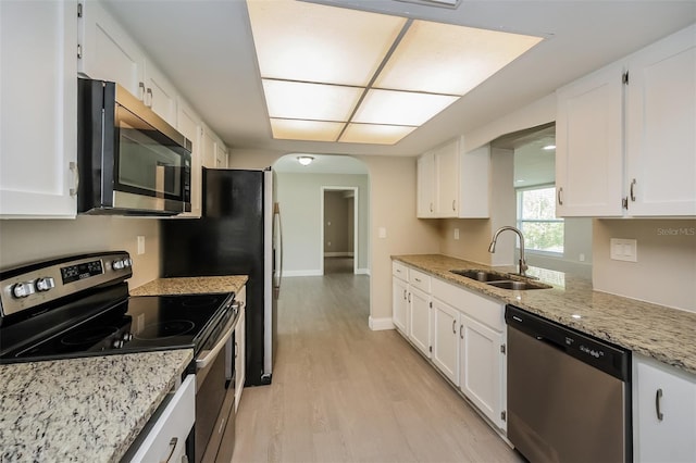 kitchen featuring sink, stainless steel appliances, light stone counters, light hardwood / wood-style flooring, and white cabinets