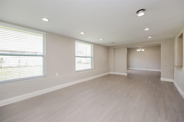 spare room featuring a chandelier and hardwood / wood-style floors