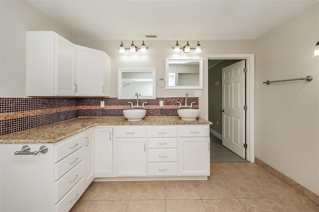 kitchen featuring white cabinets, backsplash, light stone counters, and sink