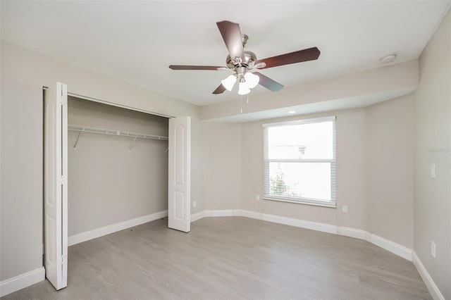 unfurnished bedroom featuring ceiling fan, light wood-type flooring, and a closet