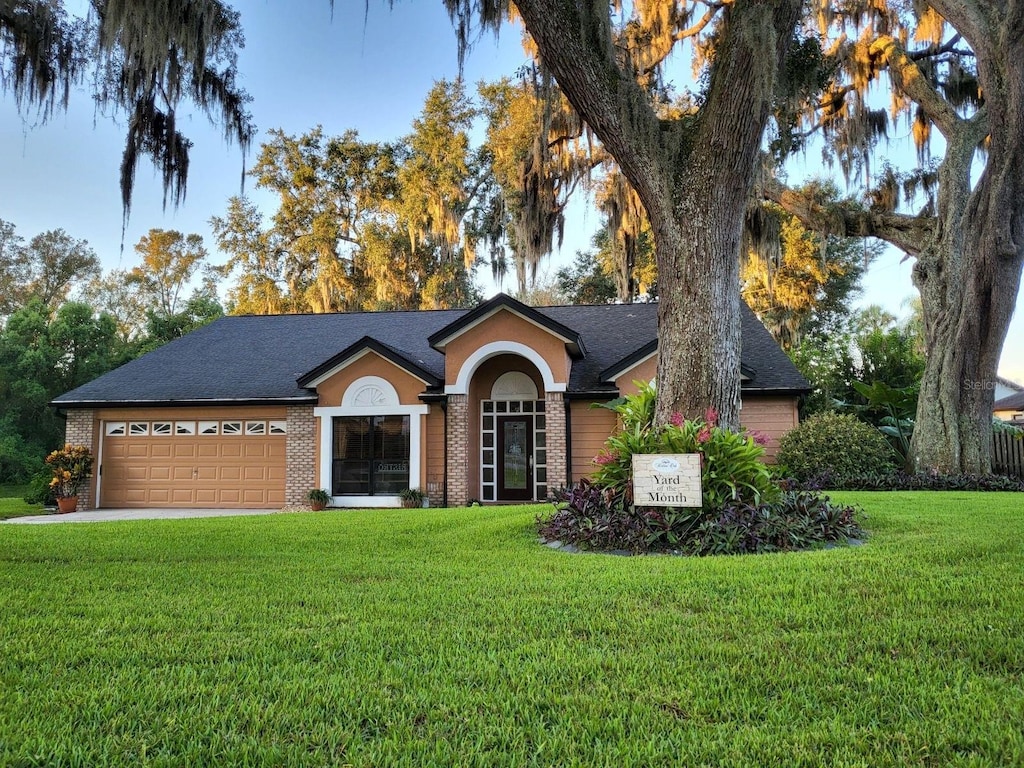 ranch-style house with a garage and a front lawn