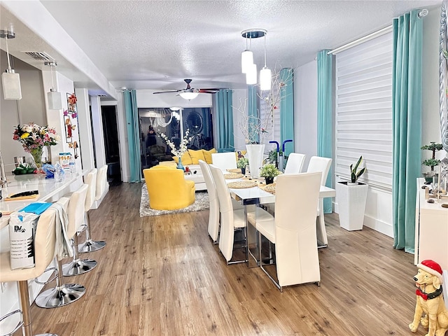 dining room featuring ceiling fan, light hardwood / wood-style floors, and a textured ceiling