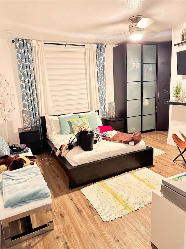 bedroom with a textured ceiling, hardwood / wood-style flooring, and ceiling fan