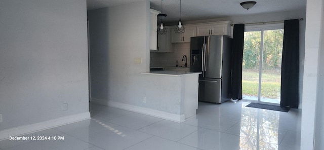 kitchen featuring pendant lighting, sink, stainless steel fridge with ice dispenser, light tile patterned floors, and white cabinetry