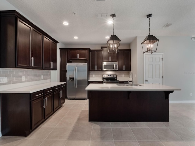 kitchen with sink, stainless steel appliances, decorative backsplash, light tile patterned flooring, and decorative light fixtures