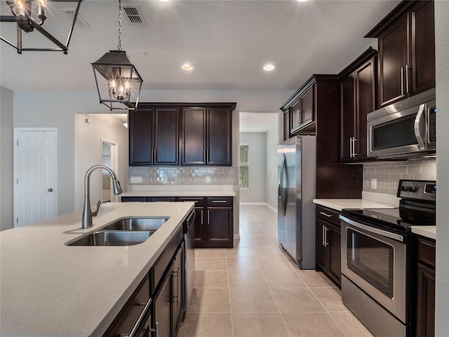 kitchen with sink, light tile patterned floors, appliances with stainless steel finishes, an inviting chandelier, and decorative light fixtures