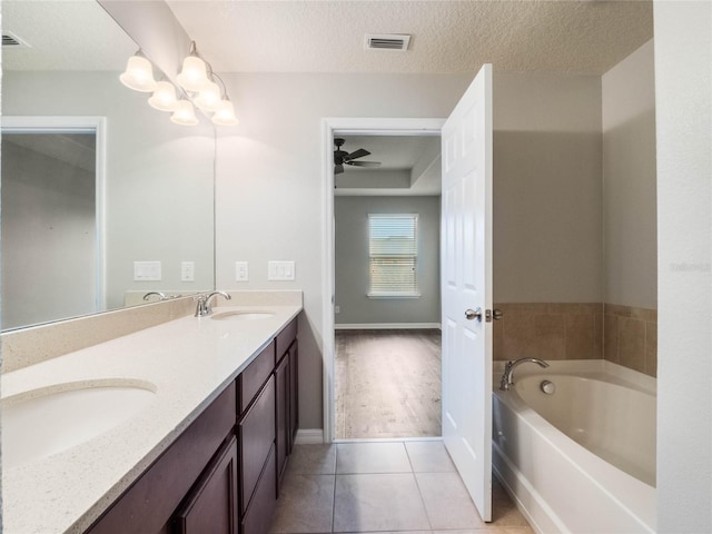 bathroom featuring ceiling fan, vanity, a textured ceiling, tile patterned floors, and a tub