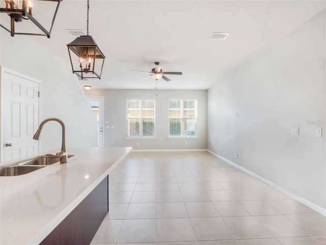 kitchen with hanging light fixtures, sink, ceiling fan with notable chandelier, and light tile patterned floors