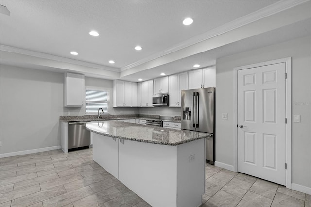 kitchen featuring appliances with stainless steel finishes, a center island, white cabinetry, dark stone countertops, and sink