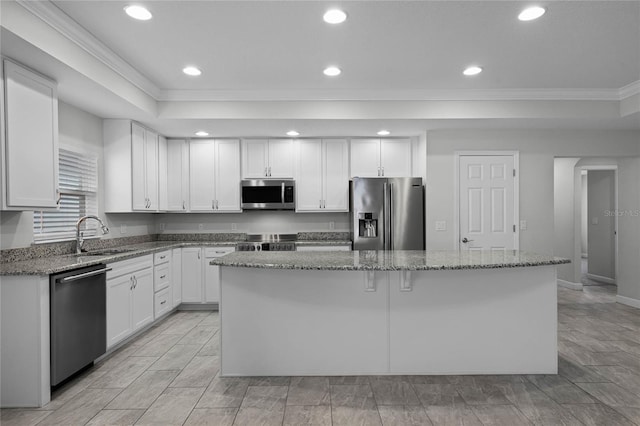 kitchen with white cabinets, dark stone counters, stainless steel appliances, and a center island