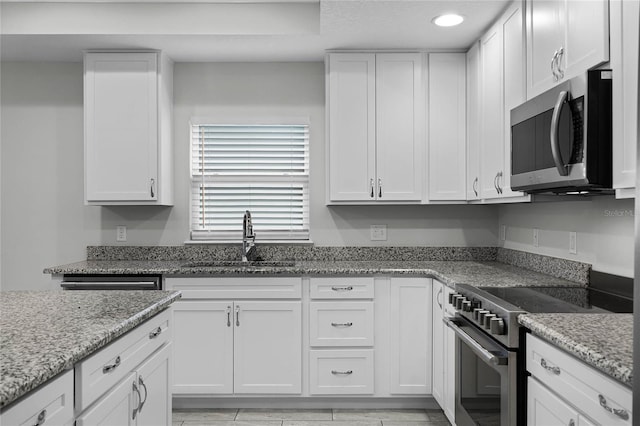 kitchen featuring sink, light stone counters, stainless steel appliances, and white cabinetry