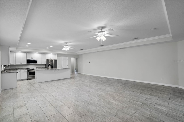 kitchen featuring ceiling fan, a raised ceiling, sink, appliances with stainless steel finishes, and white cabinets