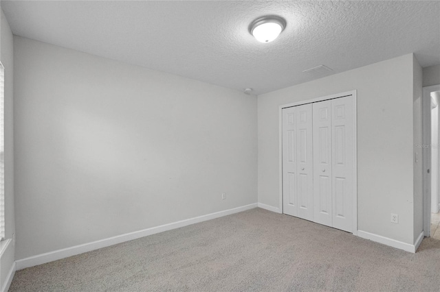 unfurnished bedroom with light colored carpet, a closet, and a textured ceiling