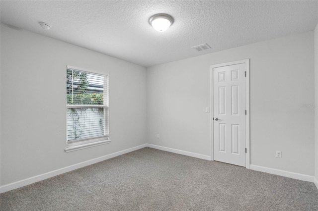 carpeted empty room with a textured ceiling