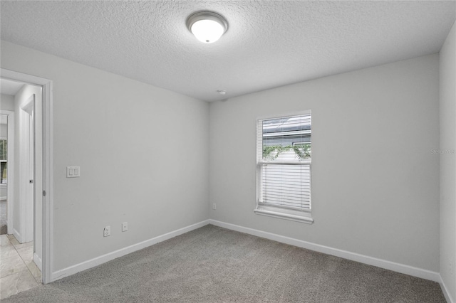 spare room featuring light colored carpet and a textured ceiling