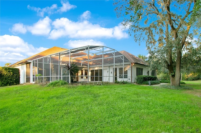 rear view of house with glass enclosure and a yard