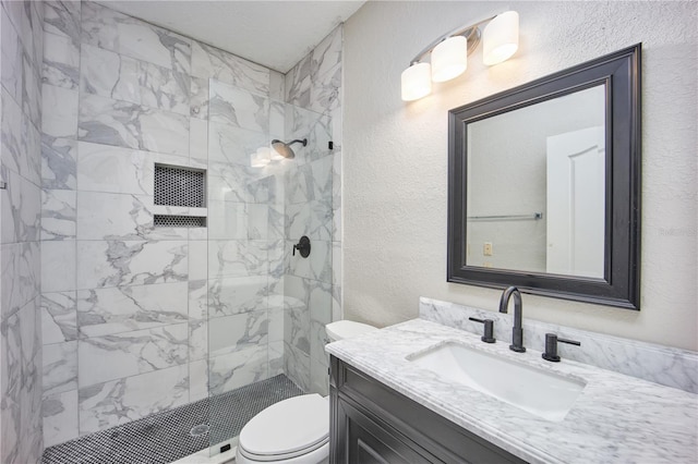 bathroom featuring vanity, toilet, and tiled shower