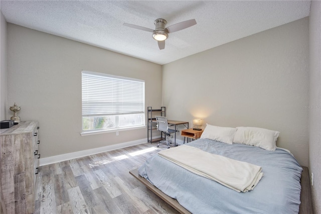 bedroom with ceiling fan, a textured ceiling, and light wood-type flooring