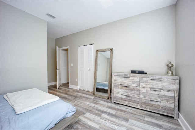 bedroom featuring a textured ceiling, light hardwood / wood-style flooring, and a closet