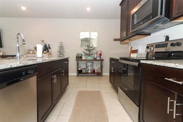 kitchen featuring appliances with stainless steel finishes, light tile patterned floors, light stone counters, and sink