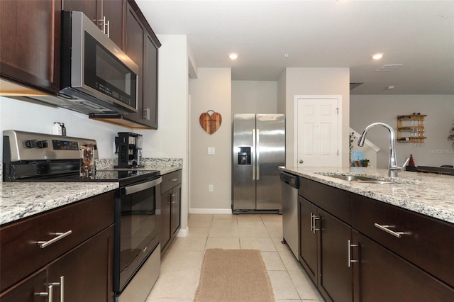 kitchen featuring light tile patterned flooring, stainless steel appliances, light stone countertops, and sink