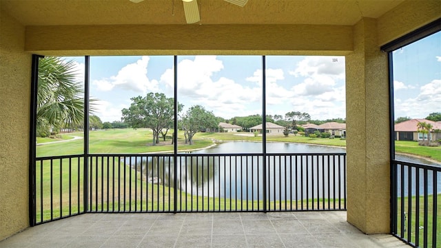 unfurnished sunroom featuring ceiling fan and a water view