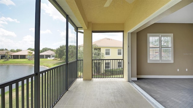 unfurnished sunroom featuring a water view, plenty of natural light, and ceiling fan