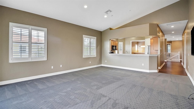 unfurnished living room featuring dark colored carpet and lofted ceiling