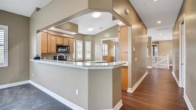 kitchen with kitchen peninsula, dark wood-type flooring, a wealth of natural light, and vaulted ceiling