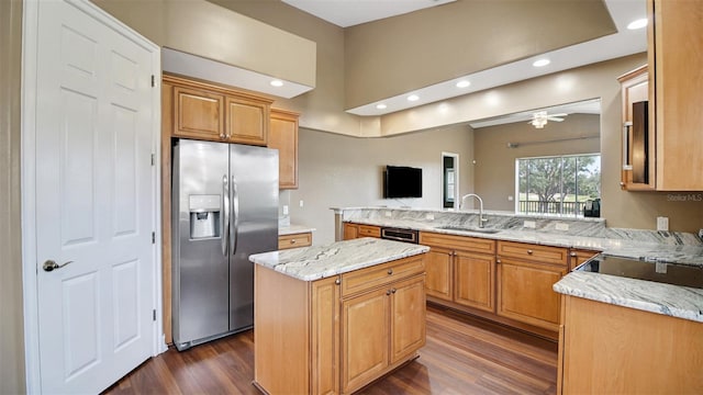 kitchen with light stone countertops, stainless steel fridge, ceiling fan, sink, and a center island