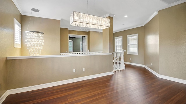 unfurnished room featuring ceiling fan with notable chandelier, crown molding, and dark wood-type flooring