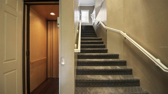 stairs with elevator, crown molding, and hardwood / wood-style flooring